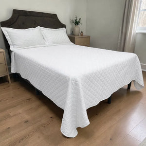 Cubrecama HPC Polo blanco acolchado, vista lateral sobre cama con dos fundas de almohada blancas.