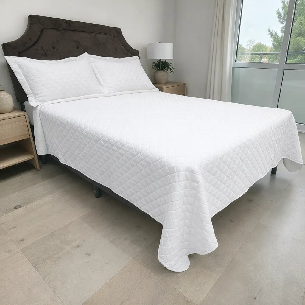 Cubrecama HPC Polo blanco sobre cama, vista lateral derecha en dormitorio con ventana y dos fundas de almohada.