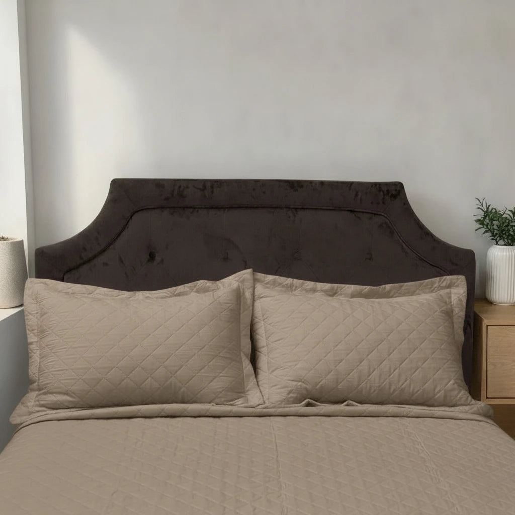 Acercamiento del cubrecama HPC Polo color camel con dos fundas de almohada acolchadas sobre cama.