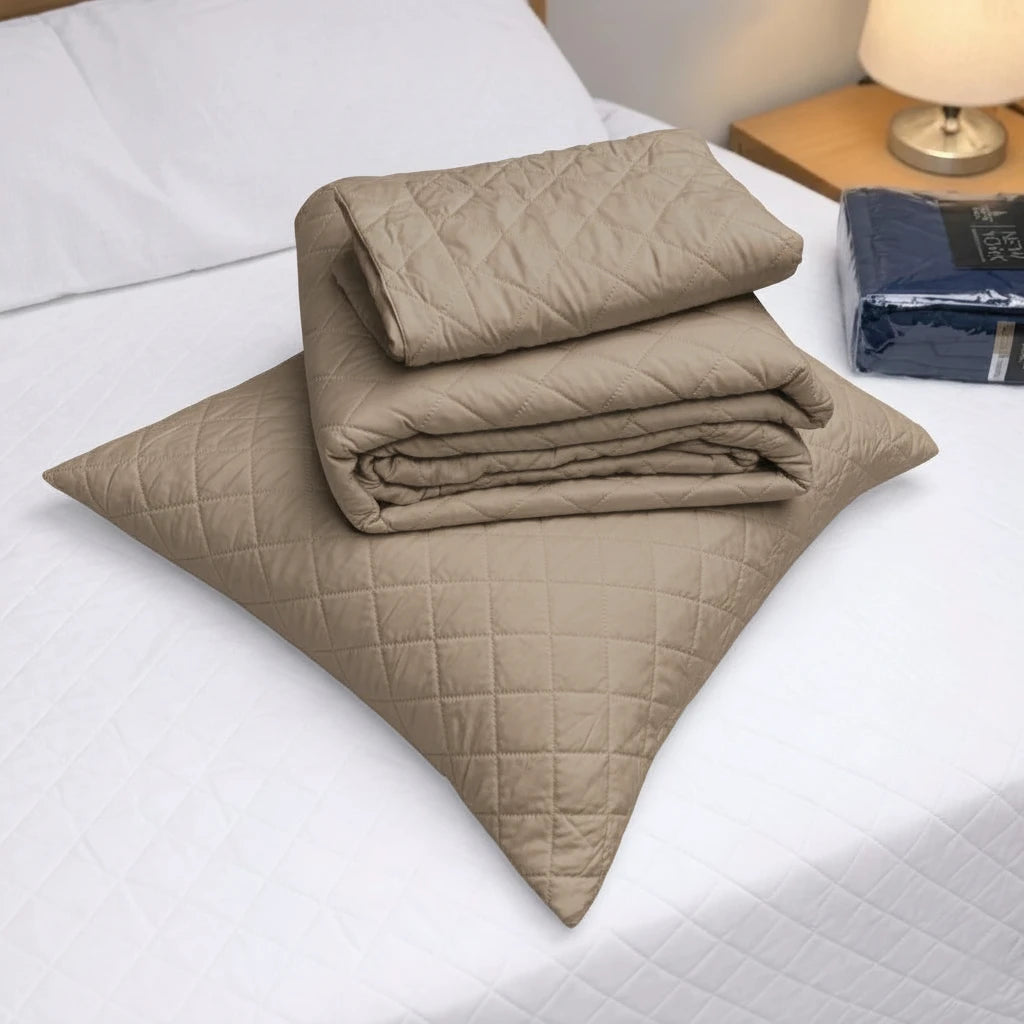 Detalle del cubrecama HPC Polo color camel doblado sobre almohada, con diseño acolchado y acabado de microfibra.