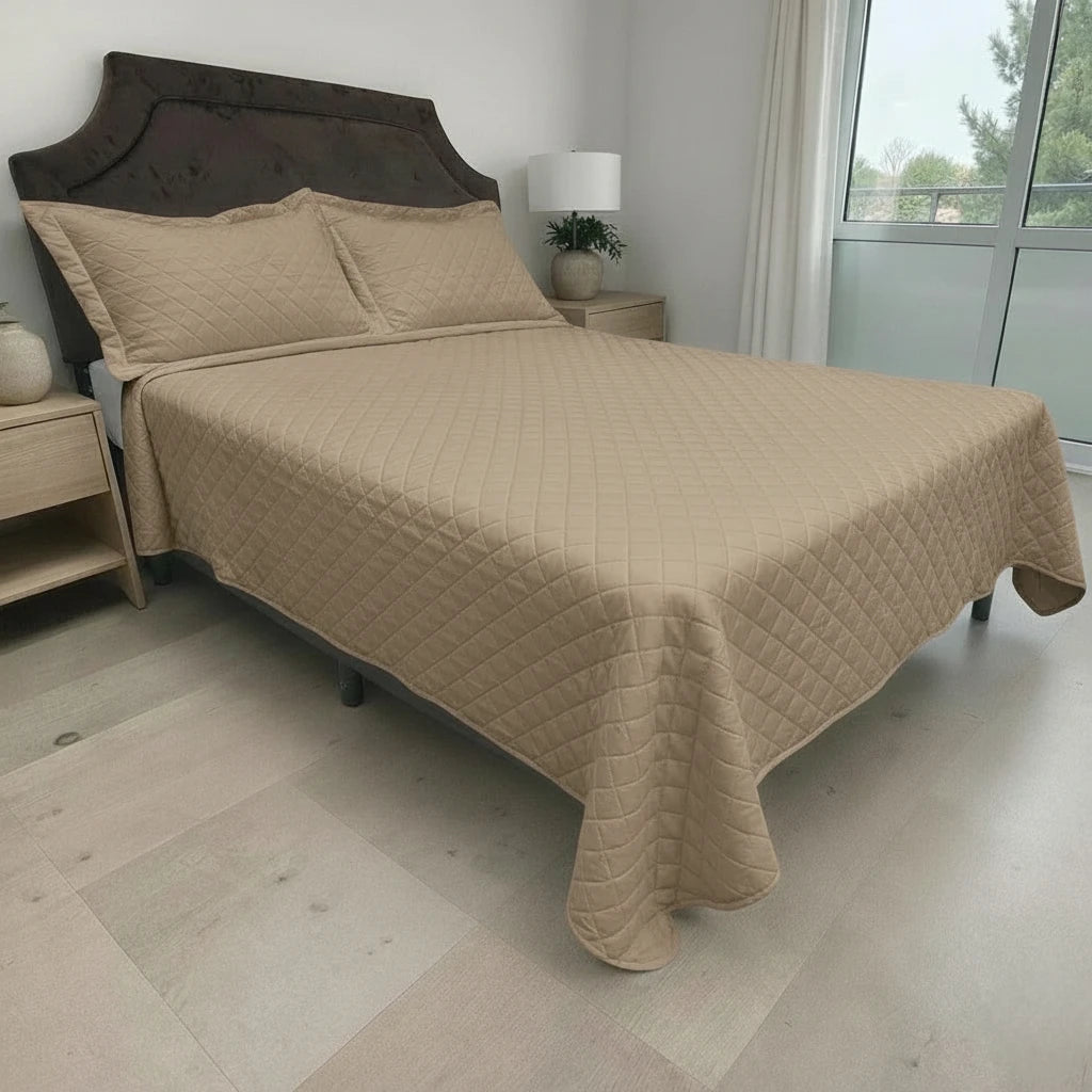 Cubrecama HPC Polo color camel sobre cama, vista lateral derecha en dormitorio con ventana y fundas de almohada a juego.