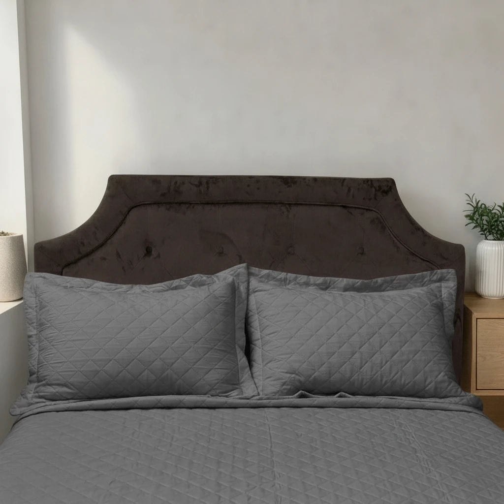 Acercamiento del cubrecama HPC Polo color gris con dos fundas de almohada acolchadas sobre cama.