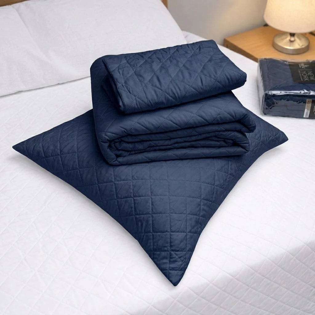 Detalle del cubrecama HPC Polo color navy doblado sobre almohada, con diseño acolchado y acabado de microfibra.