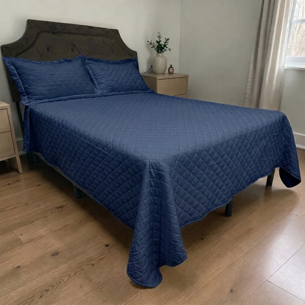 Cubrecama HPC Polo color navy acolchado, vista lateral sobre cama con dos fundas de almohada del mismo color.