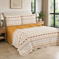 Juego de cubrecama reversible boho de 4 piezas en marfil, ocre y terracota sobre una cama.
