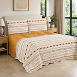 Juego de cubrecama reversible boho de 4 piezas en marfil, ocre y terracota sobre una cama.