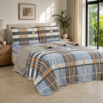 Juego de cubrecama reversible de cuadros azul, gris y mostaza instalado en un dormitorio contemporáneo.