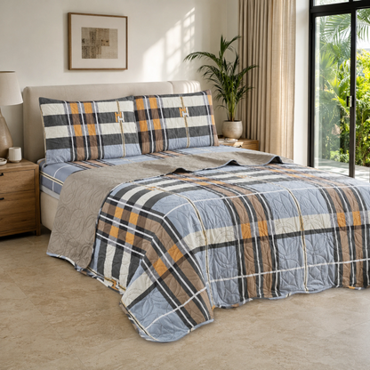 Juego de cubrecama reversible de cuadros azul, gris y mostaza instalado en un dormitorio contemporáneo.