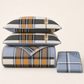 Juego de cubrecama reversible de 4 piezas con cuadros azul, gris, café y mostaza, presentado doblado.
