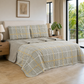 Juego de cubrecama reversible gris con cuadros blancos y mostaza, presentado sobre una cama.