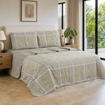 Juego de cubrecama reversible gris con cuadros blancos y mostaza, presentado sobre una cama.