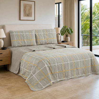Juego de cubrecama reversible gris con cuadros blancos y mostaza, presentado sobre una cama.