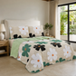Juego de cubrecama reversible beige con flores blancas, negras y verdes con centros naranja.