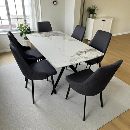 Juego de comedor Ambienta Home Decor modelo DT-06-2237 con mesa rectangular 156×86×76 cm, tapa efecto mármol blanco y seis sillas tapizadas gris oscuro con patas metálicas negras, vista frontal junto a la ventana.