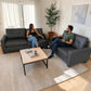 Juego de sofá 3+2 SF-711-GREY en cuero sintético gris oscuro con dos personas usándolo en sala moderna, mostrando comodidad y uso real en el hogar.