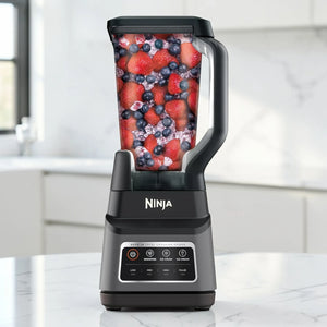 Licuadora Ninja Professional Plus con Auto-IQ BN701 en color gris oscuro y negro, vista frontal sobre encimera de cocina, con vaso transparente de 72 oz lleno de fresas, arándanos y hielo.