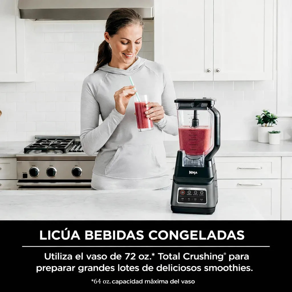 Licuadora Ninja Professional Plus BN701 sobre encimera de cocina moderna junto a una mujer sosteniendo un vaso de smoothie rojo, mostrando su uso para bebidas congeladas.