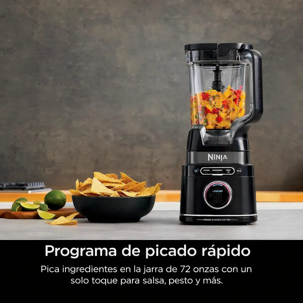 Licuadora Ninja TB301 negra con jarra de 72 onzas usando programa de picado rápido para preparar salsa, pesto y mezclas en cocina, junto a totopos y limones.