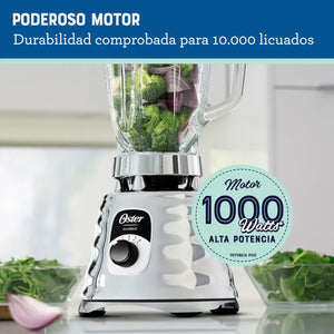 Licuadora Oster BLST4655 cromada con motor de 1000 watts, vaso de vidrio con verduras y mensaje de durabilidad para 10,000 licuados.