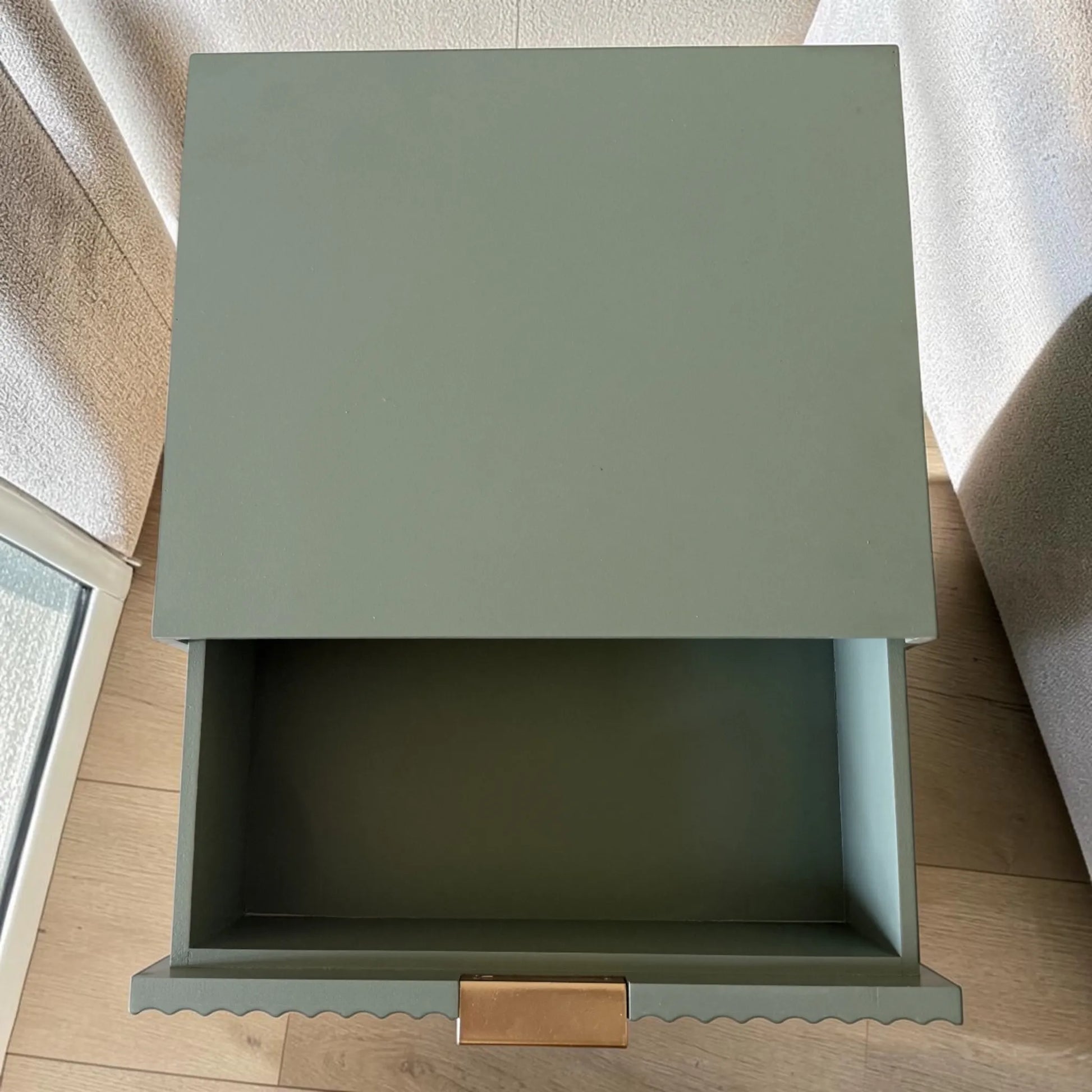 Vista superior de mesa auxiliar STUDIO-1061 verde oliva con cajón abierto, espacio interior amplio y tirador dorado.