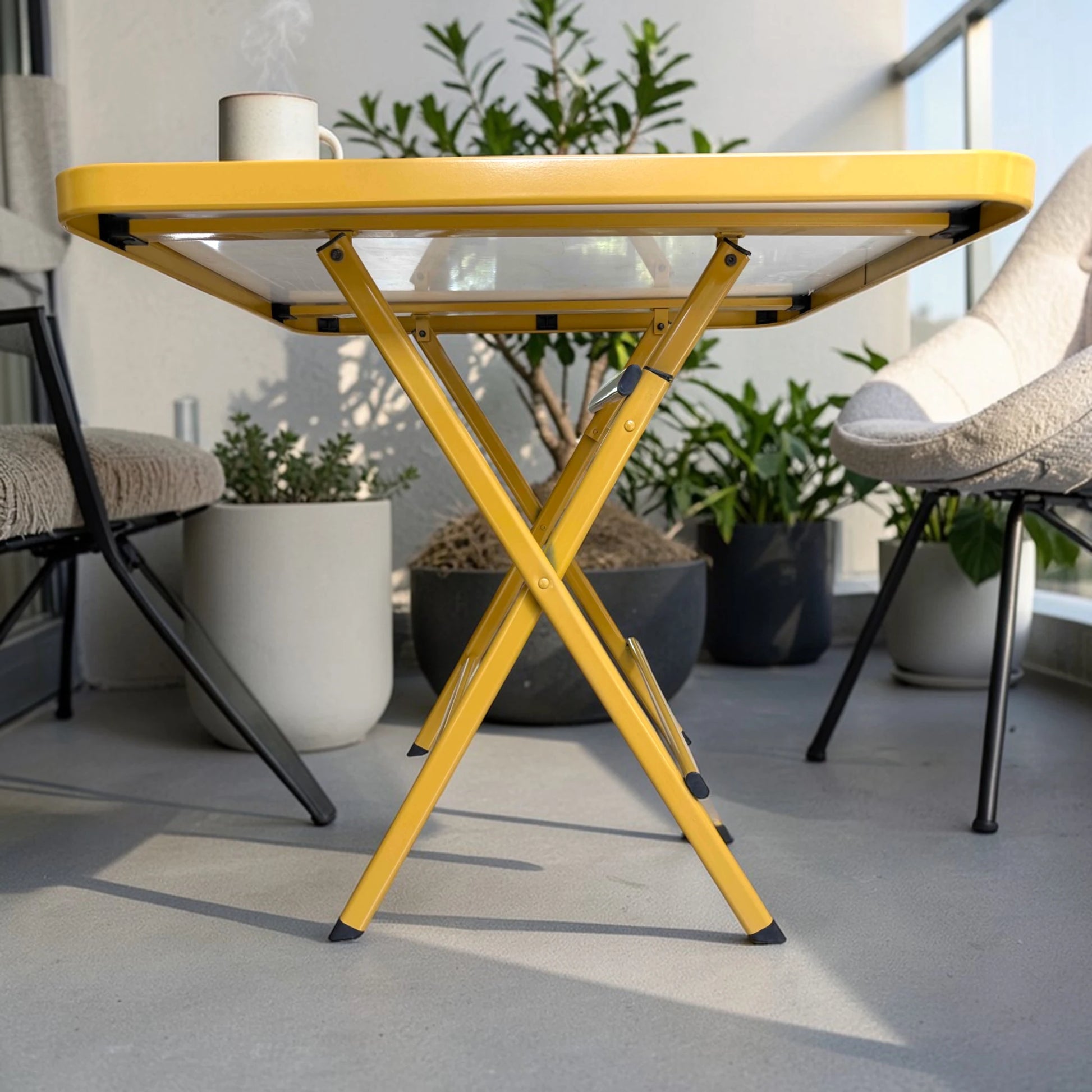 Perfil lateral bajo de mesa plegable multiusos de 80x80 cm con estructura metálica dorada y tablero cuadrado tipo mármol.