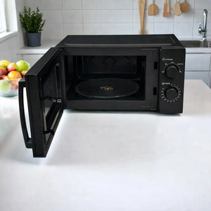 Microondas Oster OGW1702 negro de 17 L y 700 W con puerta abierta, mostrando interior y plato giratorio de vidrio, controles laterales con perillas negras y letras blancas (potencia y tiempo), colocado sobre encimera blanca en cocina.