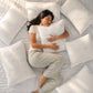 Mujer descansando sobre una cama mientras abraza una almohada de bambú Pacific Home blanca, rodeada de almohadas con tela transpirable.