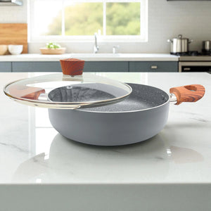 Olla baja Proctor Silex de 3.5QT en aluminio gris con tapa de vidrio abierta y mangos efecto madera, vista lateral sobre encimera de cocina.