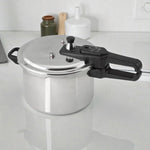 Olla de presión Black+Decker PC700 de 7 litros en aluminio plateado, vista general 3/4 sobre encimera, con manija larga negra y tapa con válvulas de seguridad.