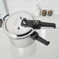 Vista superior de la olla de presión Black+Decker PC700 de 7 litros, tapa plateada con válvulas de seguridad y regulador de presión, manija negra y asa lateral.