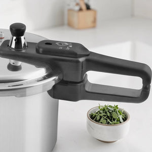 Detalle de la manija negra y sistema de cierre de seguridad de la olla de presión Black+Decker PC700 7 litros, con regulador de presión y tapa de aluminio.