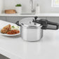 Olla de presión Black+Decker PC700 7 litros en aluminio plateado sobre isla de cocina, vista 3/4 con plato de comida al lado, manija negra y tapa con válvulas de seguridad.