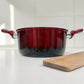 Olla Epicure Escarlata sin tapa en color rojo vino con asas laterales, fotografiada de frente sobre encimera blanca en cocina moderna.