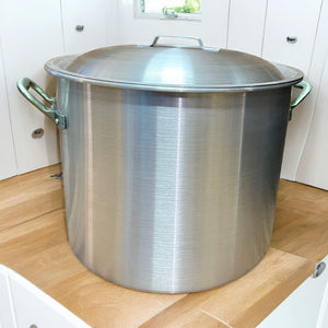 Olla de aluminio industrial grande con tapa colocada en encimera de cocina