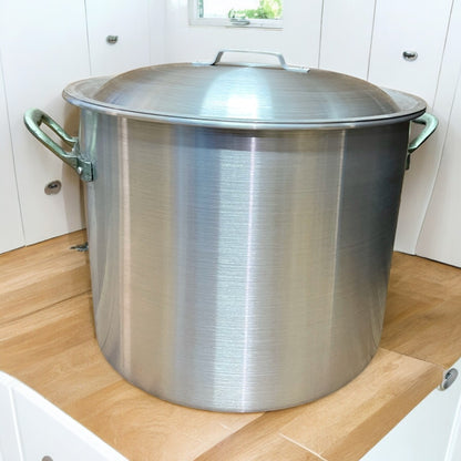 Olla de aluminio industrial grande con tapa colocada en encimera de cocina