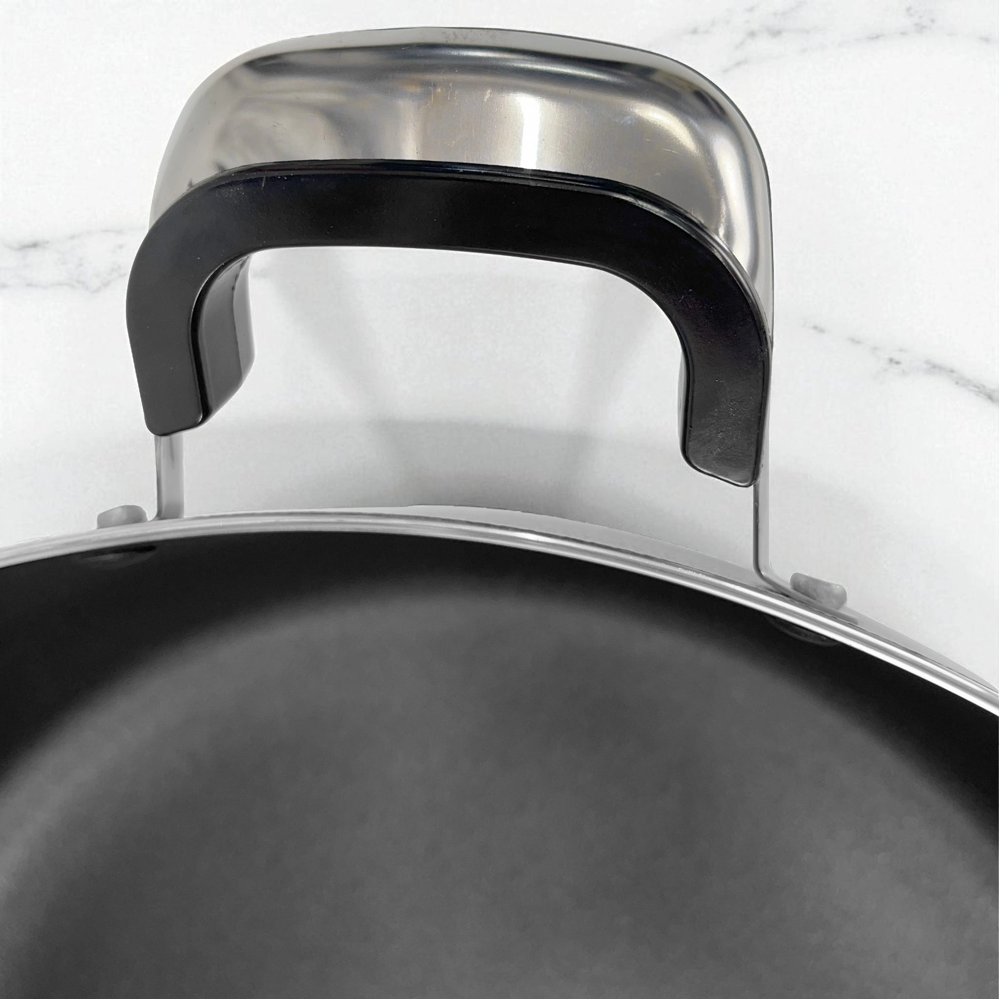 Detalle de las asas Bake-lite resistentes al calor en olla antiadherente ROCA con exterior de granito negro y tamaño 38x16 cm.