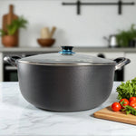 Olla antiadherente ROCA con exterior de granito color negro, tapa de vidrio templado y asas Bake-lite, tamaño 38x16 cm, vista frontal sobre mesa de cocina.