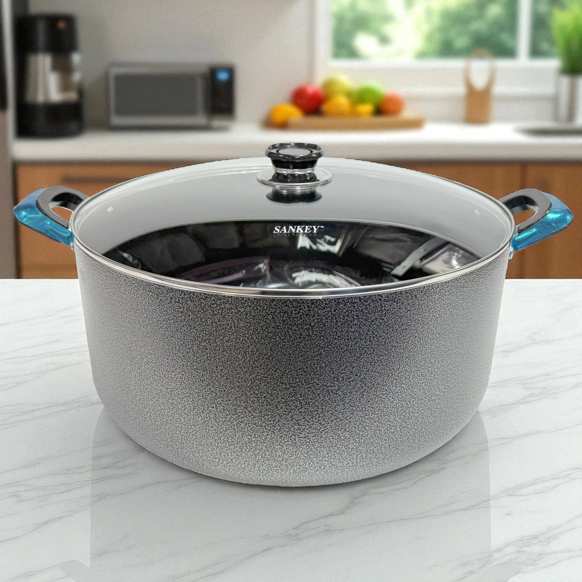 Olla de cerámica antiadherente Sankey de 38 cm con tapa de vidrio y mangos azul metálico, vista frontal sobre encimera blanca