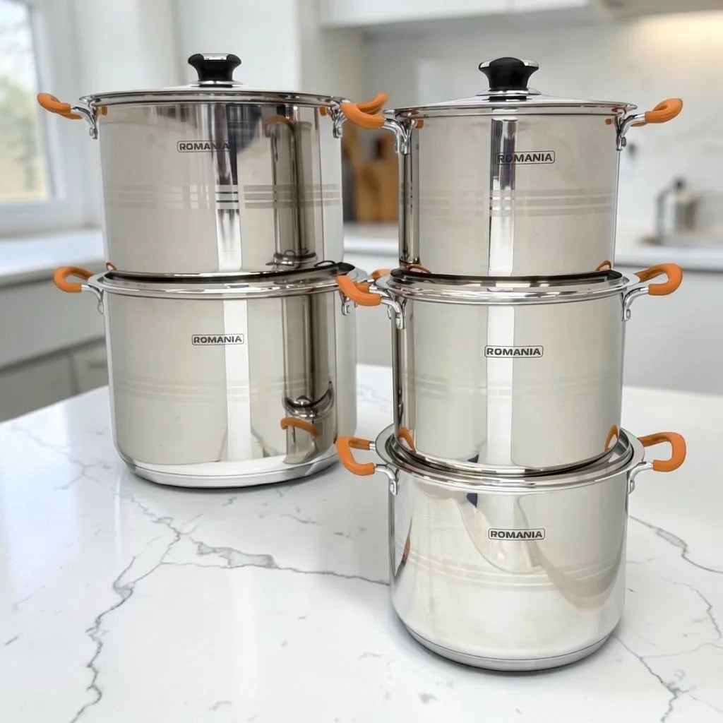 Ollas Romania de acero inoxidable con mangos naranjas en composición frontal apilada sobre encimera blanca de cocina.