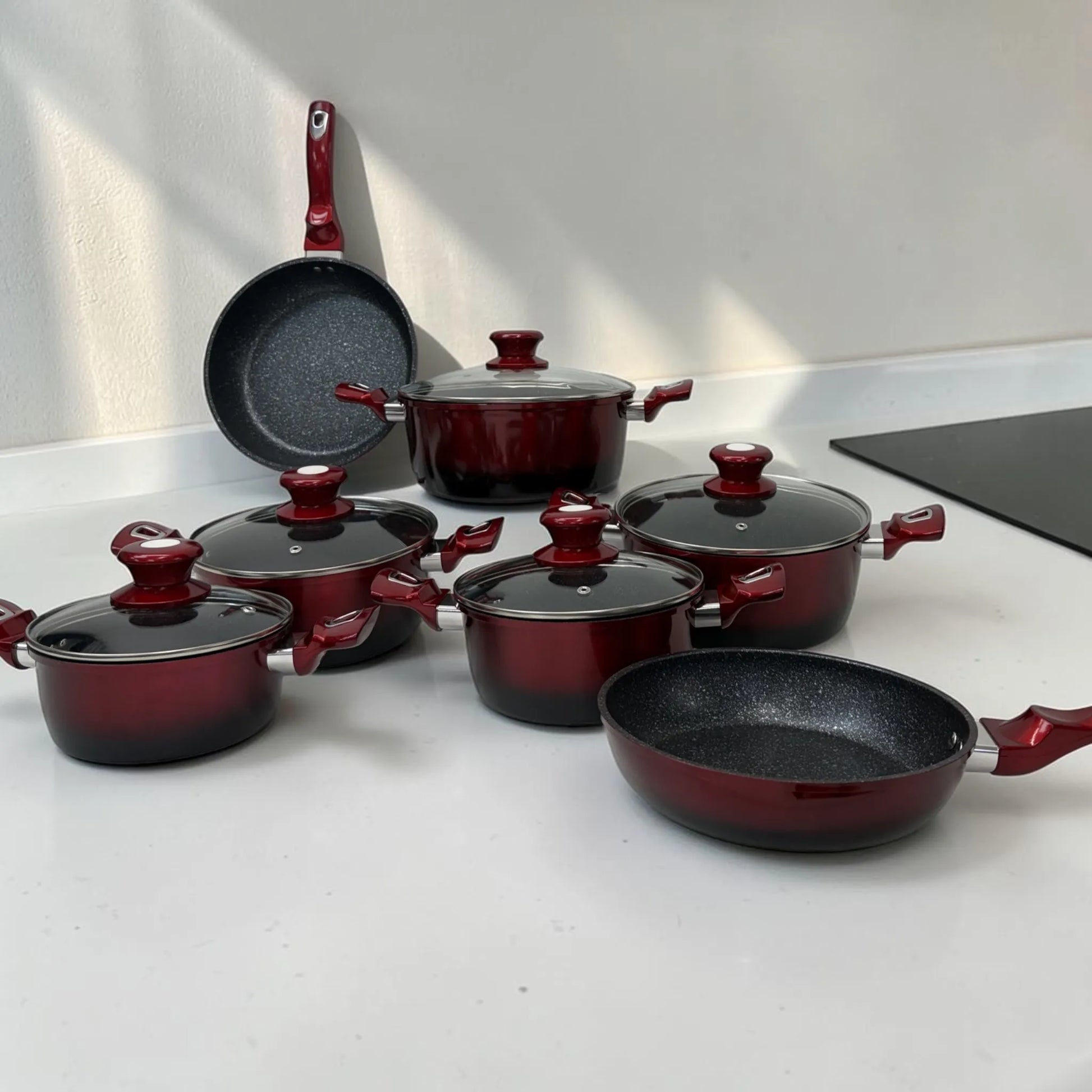 Ollas y sartenes Epicure Escarlata de 12 piezas en color rojo vino con tapas de vidrio y antiadherente tipo mármol, SKU EP-12PCS-045, en cocina moderna.