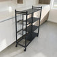Vista lateral trasera del organizador de cocina metálico Ambienta Home Decor con cuatro repisas, tres canastas metálicas y ruedas giratorias en cocina contemporánea.