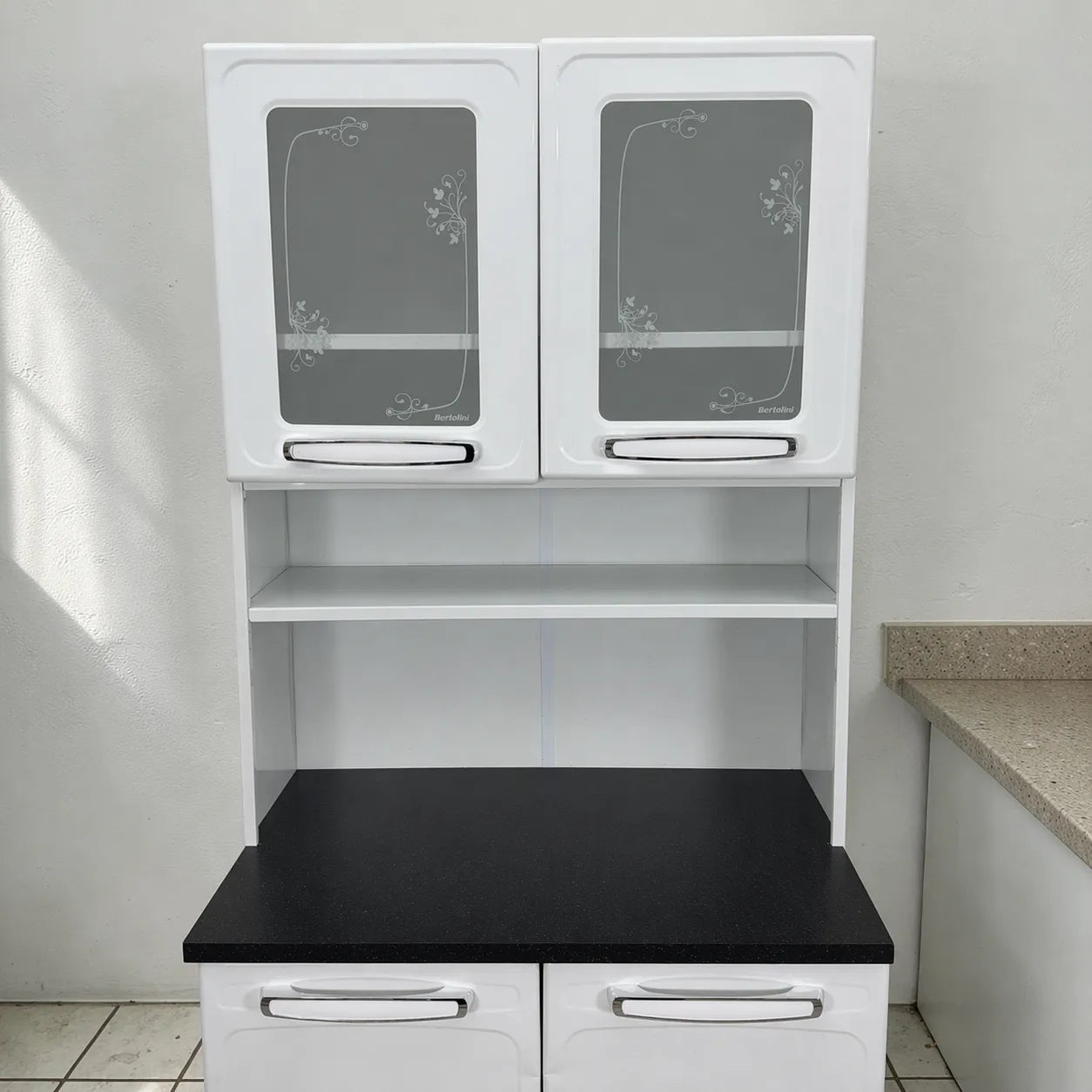 Vista frontal cercana del organizador de cocina 2x1 Bertolini blanco con tablero negro, puertas superiores decoradas y compartimento central abierto.