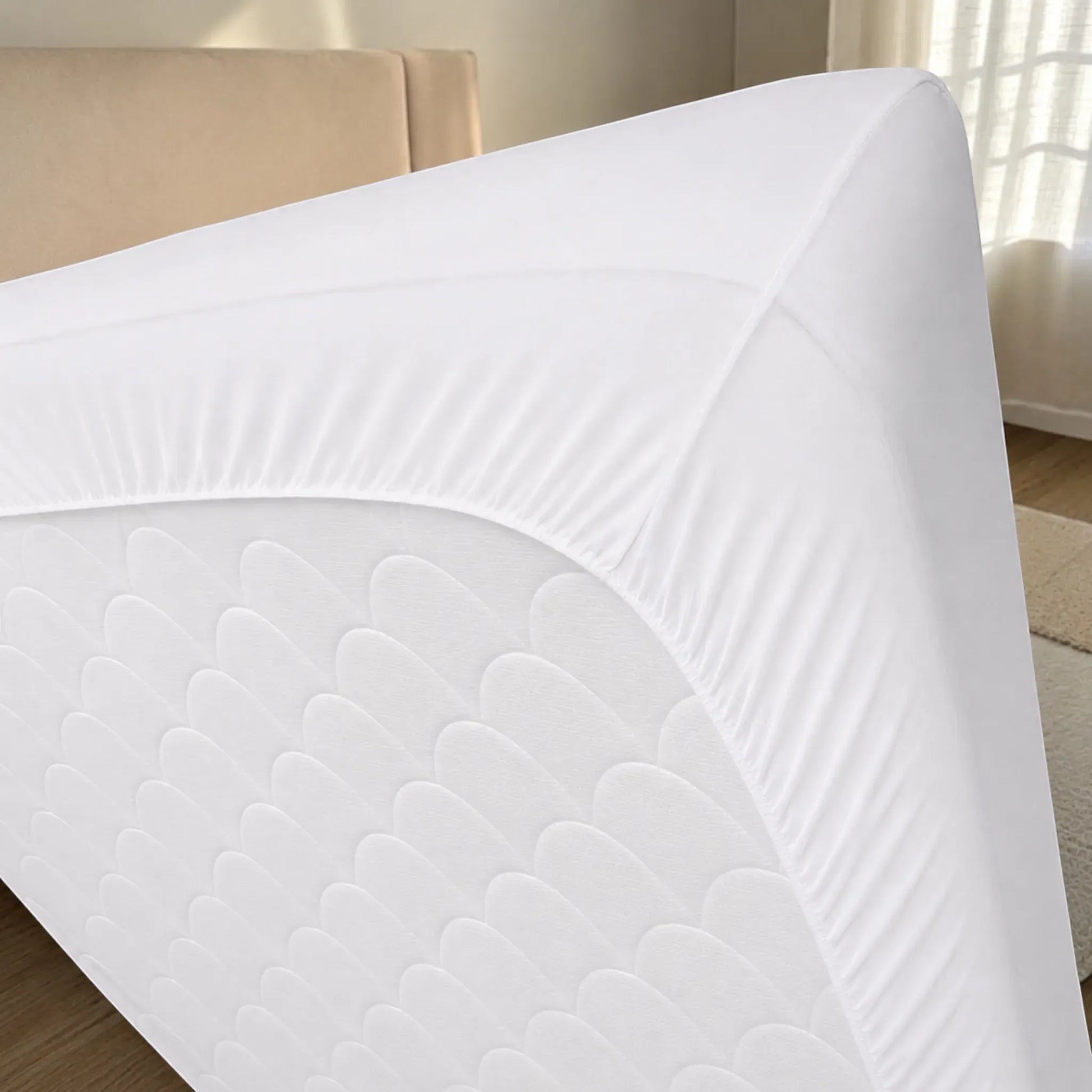 Detalle de la parte inferior del protector de colchón blanco con falda de bolsillo profundo y elástico perimetral para sujetarse firmemente al colchón.