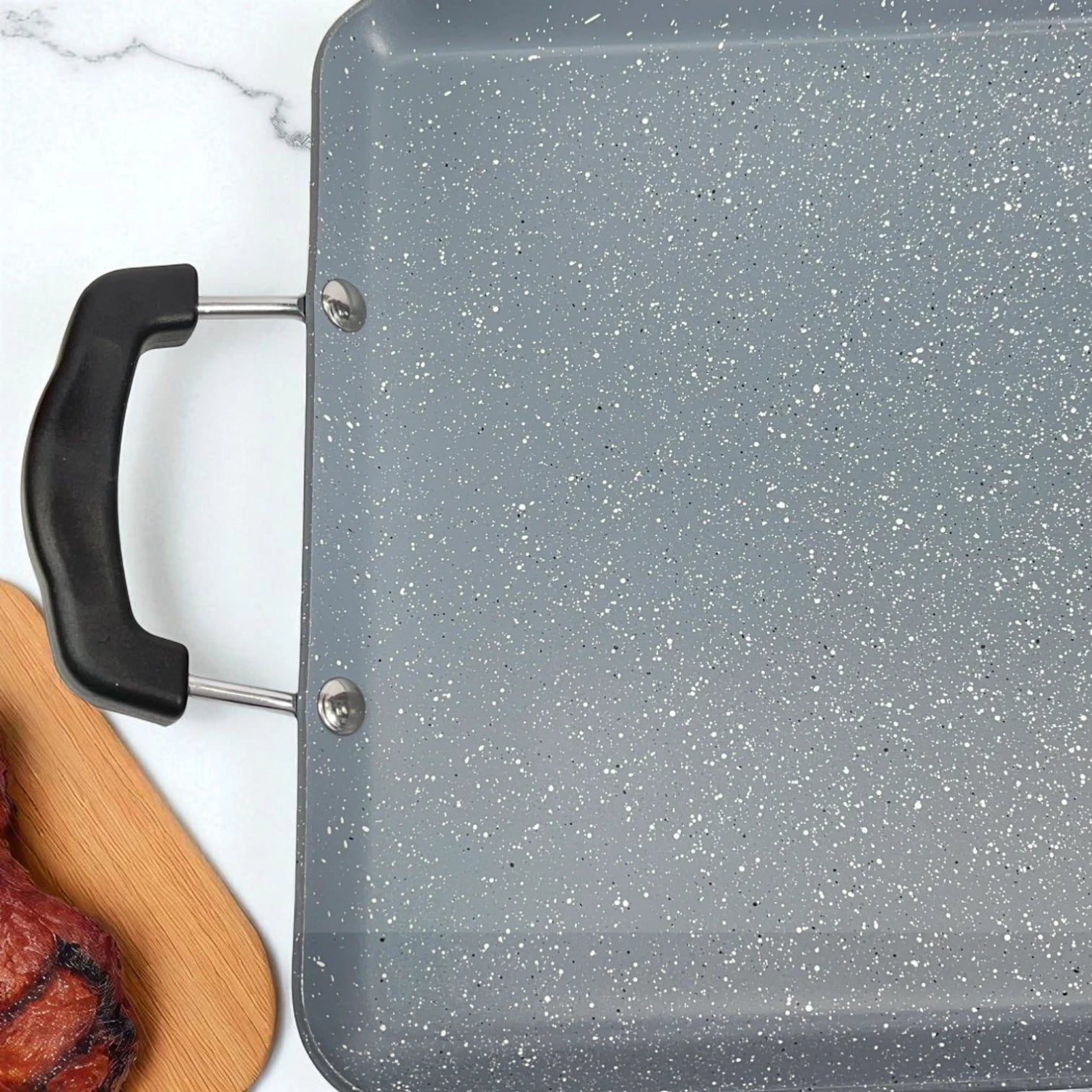 Vista cercana de la plancha Estrella Gourmet de doble quemador 48x29 cm, con superficie marmolizada gris antiadherente y asas negras.