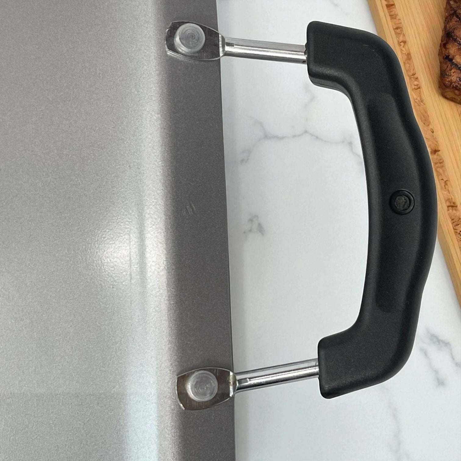 Reverso de la plancha Estrella Gourmet de doble quemador en acero plateado con asas negras resistentes al calor.