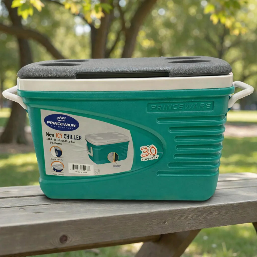 Hielera grande Princeware New Icy Chiller 30L cerrada, color turquesa con detalles blanco/gris, con porta vasos integrados en la tapa, colocada sobre mesa de picnic en parque.
