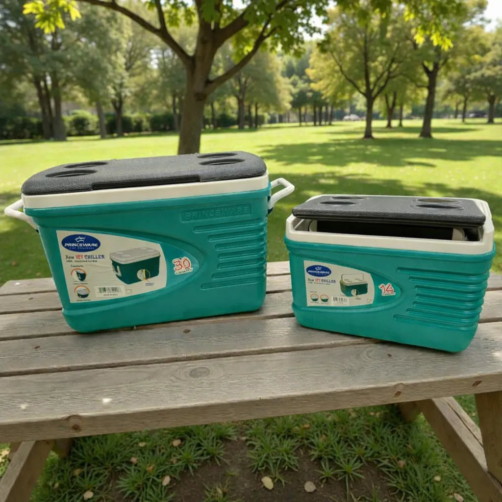 Hieleras Princeware New Icy Chiller 30L y 14L sobre mesa de picnic en parque; la 30L con tapa levantada y la 14L con tapa semi abierta, color turquesa con detalles blanco/gris (set 3409-C1PB).