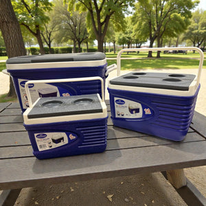 Set de 3 hieleras térmicas Princeware New Icy Chiller azul con detalles blanco/gris (6L, 14L y 30L) sobre mesa de picnic en parque, con porta vasos en la tapa.