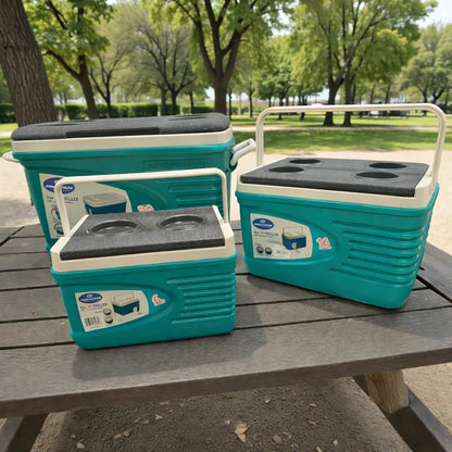 Set de 3 hieleras térmicas Princeware New Icy Chiller turquesa con detalles blanco/gris (6L, 14L y 30L) sobre mesa de picnic en parque, con porta vasos en la tapa.