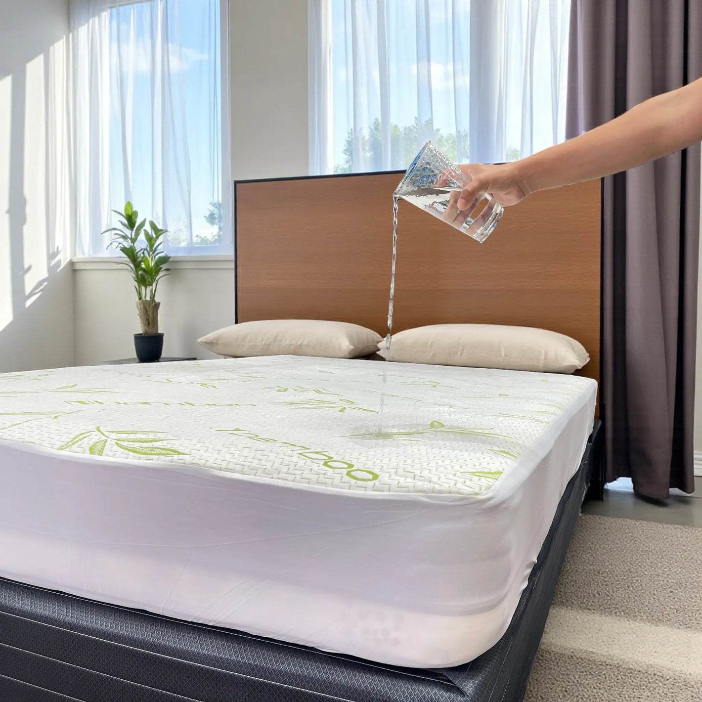 Mano vertiendo agua sobre el protector de colchón impermeable Scarlett Classics Bamboo Sensation, color blanco con diseño bambú, compatible con twin, full y queen (hasta 38 cm).